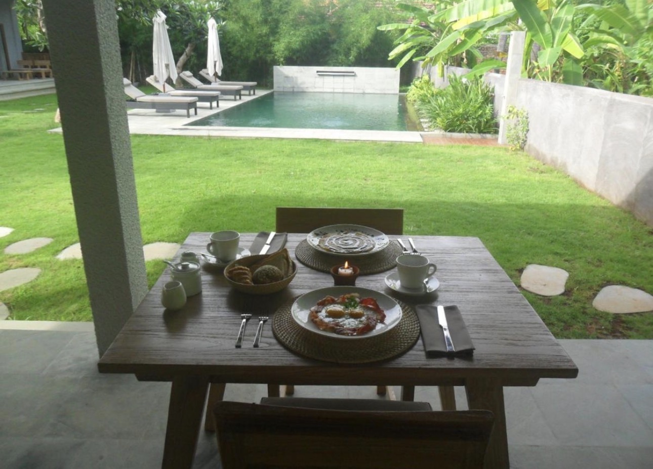 Mesa de desayuno frente a la piscina y el jardín