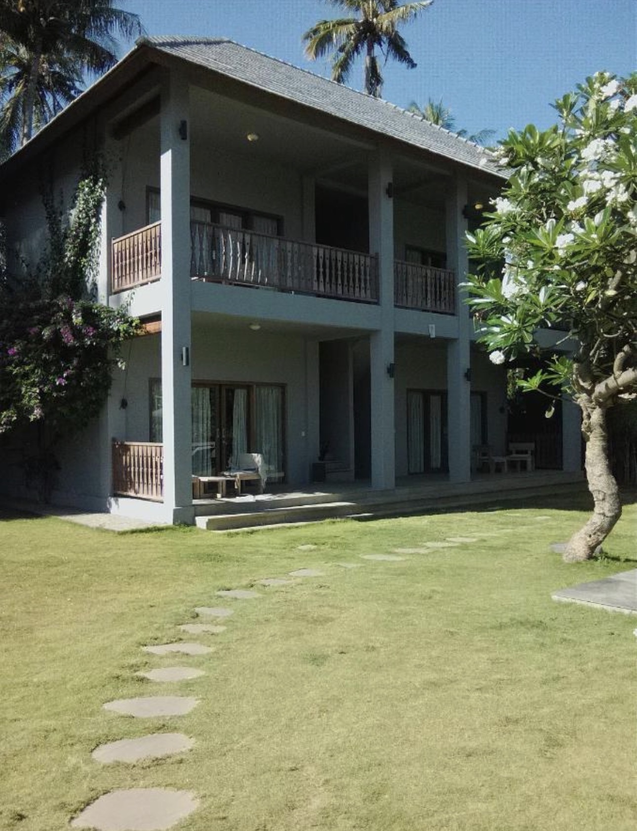 Fachada de la villa de dos pisos con camino de piedra y jardín