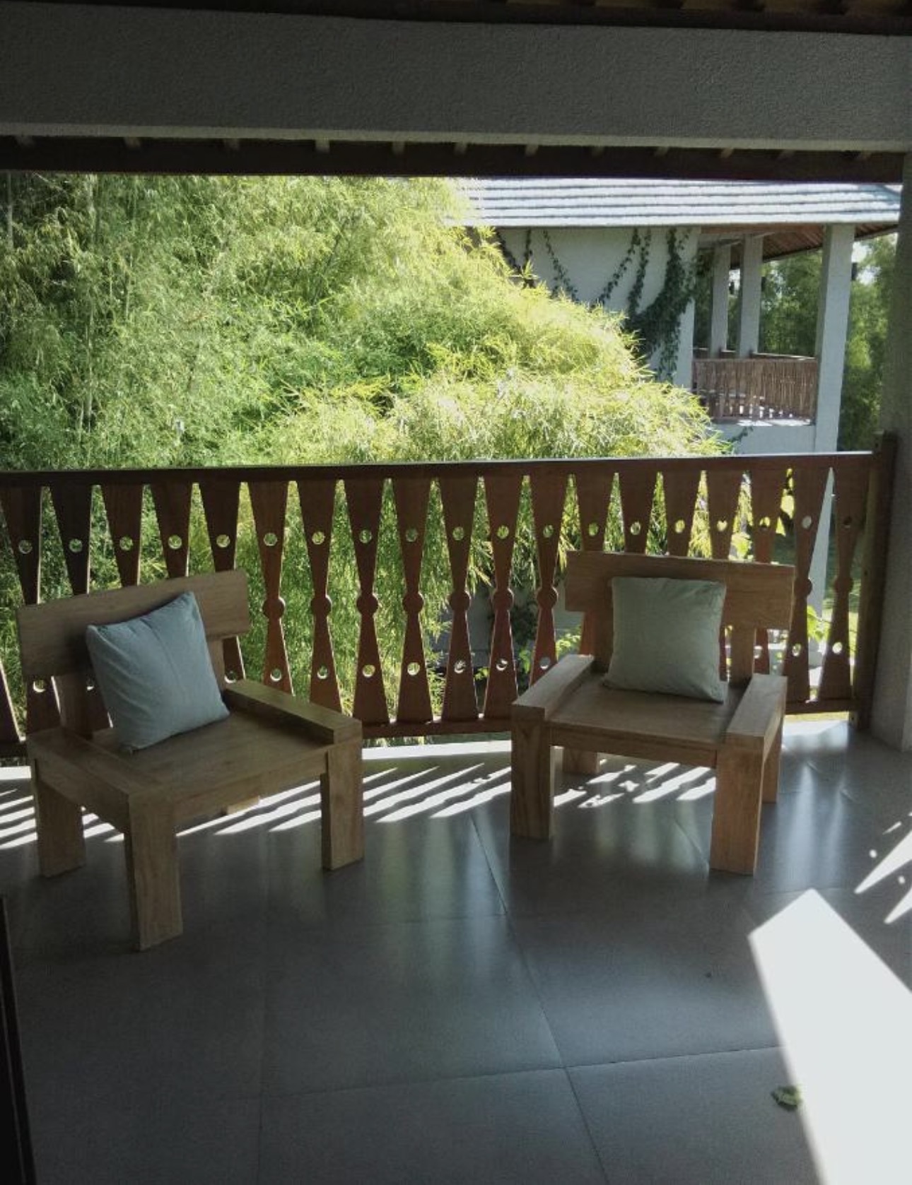 Terraza privada con sillones de madera balinesa frente al bambú